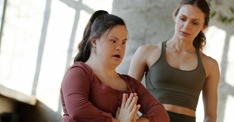 Image of an individual doing yoga with supervision from a coach