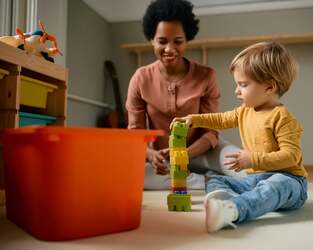 Clinician observing a child play with jumbo legos