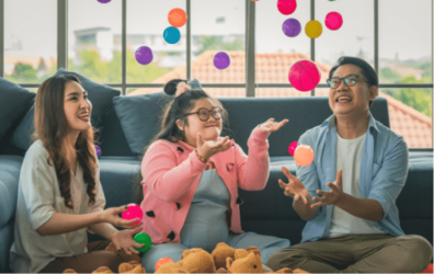 Mom, child, and dad playing with balloons on the floor at home